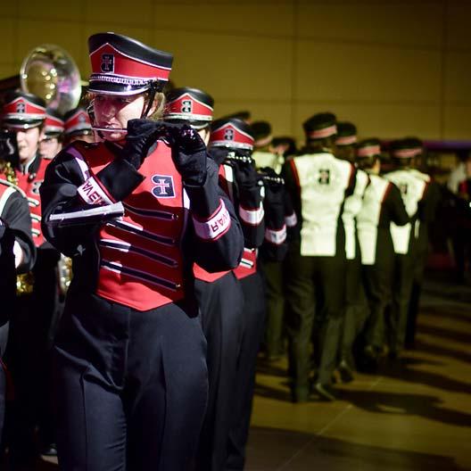 Raven Regiment flutist marching with band in the background